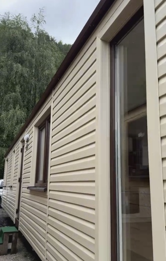 Bílý mobilní dům s hnědými okny – čelní pohled moderního domu