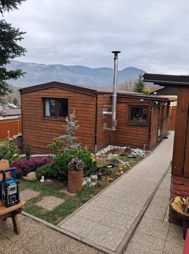 Mobilheim s verandou a dřevěným obkladem na zahradě